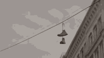 a pair of shoes hanging from a power line on the side of a building