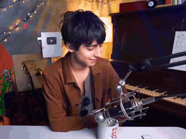 a man sitting at a table with a microphone and a cup that says " i love you "