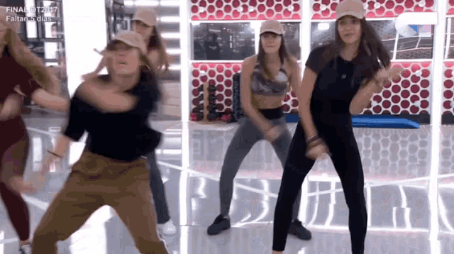 a group of women are dancing in front of a wall that has circles on it .