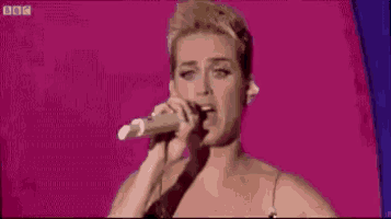 a woman is holding a microphone in front of her face on a stage .