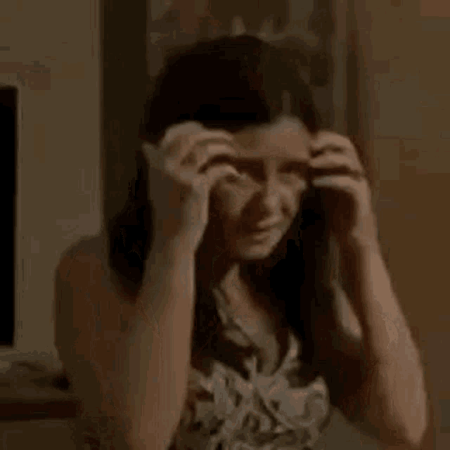 a woman is covering her mouth with her hand and looking at the camera .