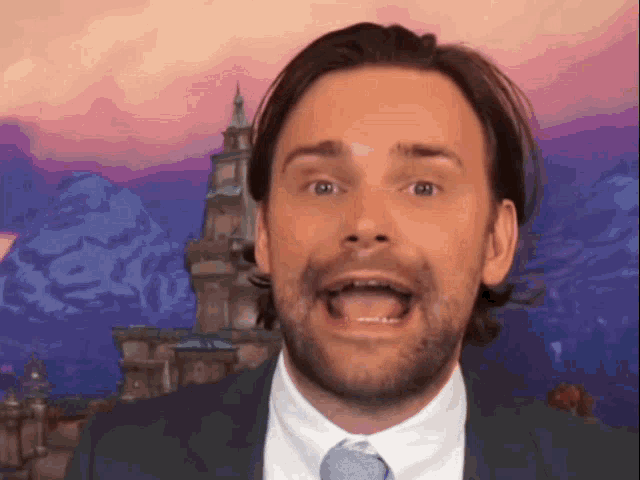 a man with a beard wearing a suit and tie is making a funny face