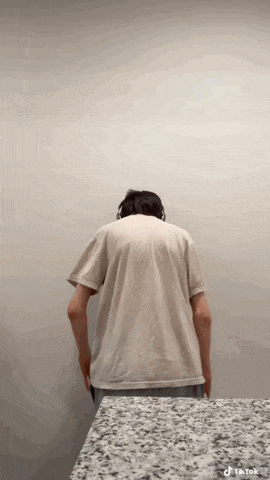 a man wearing headphones is standing in front of a wall with his back to the camera and a tiktok watermark on the bottom