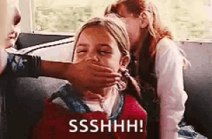 a girl is covering her mouth with her hand while another girl looks on .