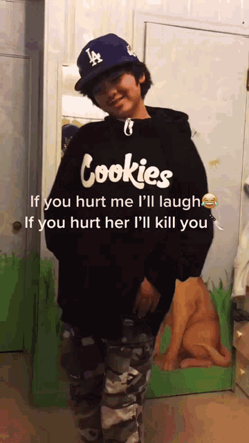 a person wearing a la hat and a hoodie that says cookies