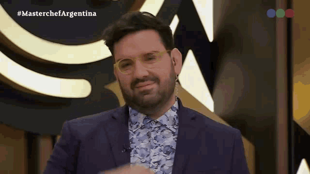 a man wearing glasses and a suit is sitting in front of a masterchef argentina logo