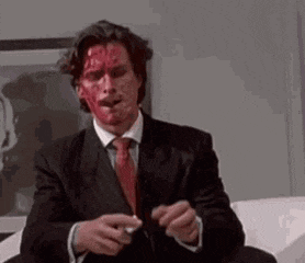 a man in a suit and tie with blood on his face is smoking a cigarette .