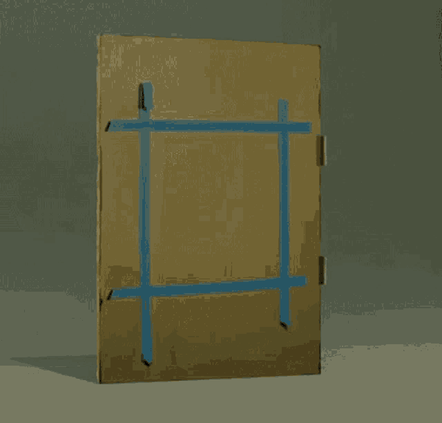 a cardboard box is sitting on top of a table with a blue tape .