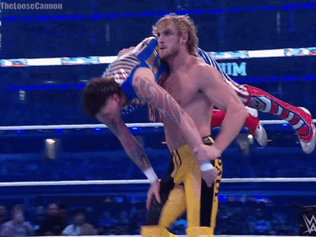 a wrestler is being lifted in the air by another wrestler in front of a sign that says at & t on it