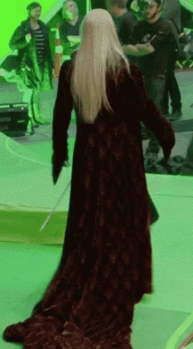 a woman in a long red dress is walking with a sword