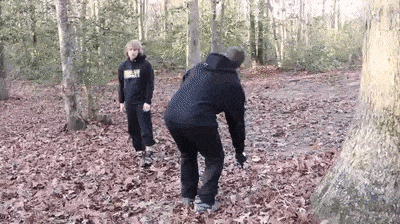 two people are standing next to each other in the woods .