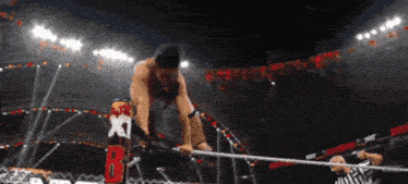 a wrestler in a ring with the letter b on a sign