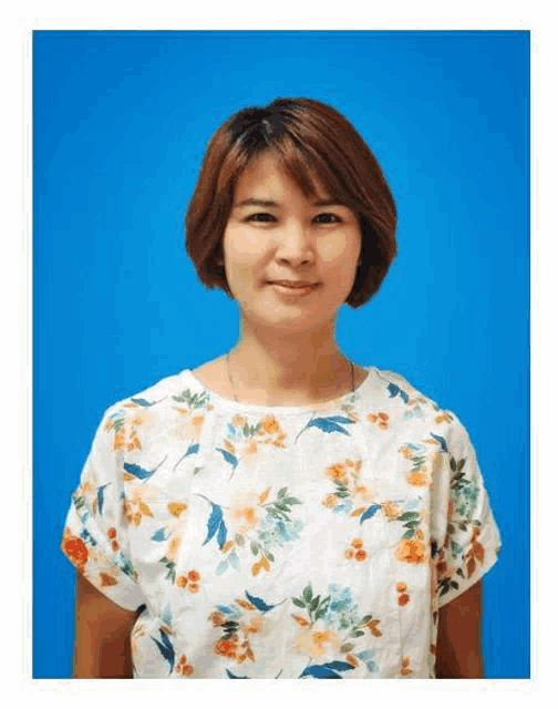 a woman is wearing a white floral shirt and standing in front of a blue background .