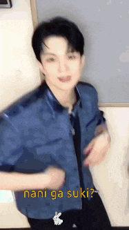 a man in a blue shirt is dancing with the words nani ga suki written on the bottom .