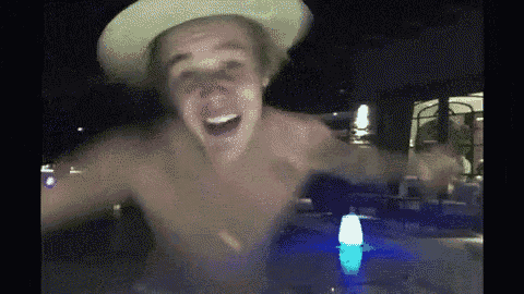 a shirtless man in a cowboy hat is standing in a hot tub at night .