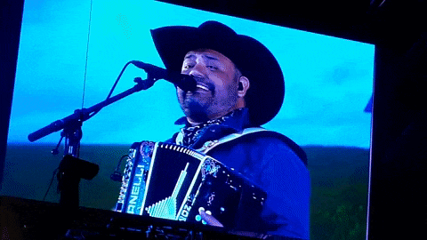 a man in a cowboy hat is singing into a microphone while holding an accordion