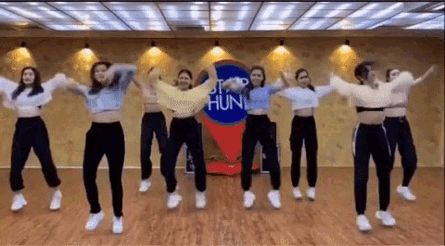 a group of women are dancing in a room with a map in the background .