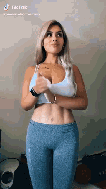 a woman is wearing a white tank top and blue leggings .