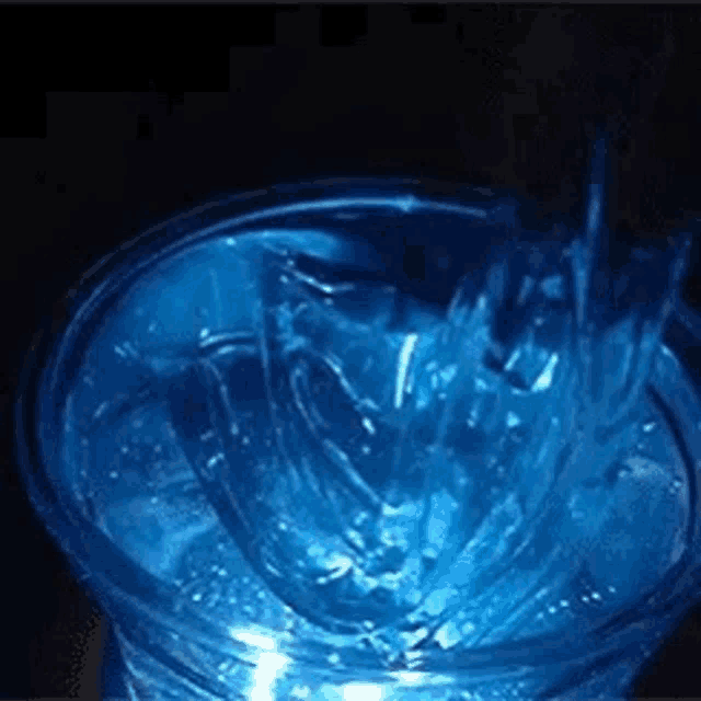 a blue cup of water is being poured into a glass .