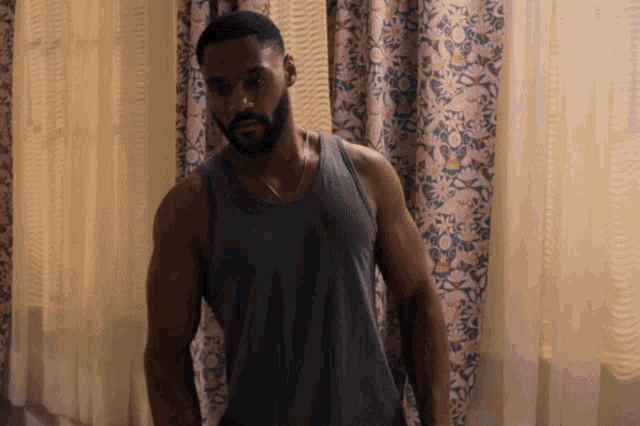 a man with a beard wearing a grey tank top