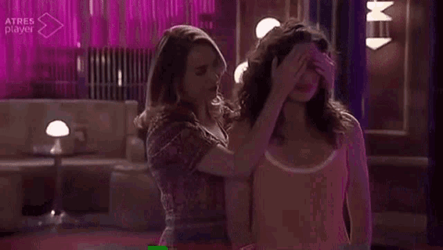 two women are standing next to each other in front of a pink curtain in a bar .