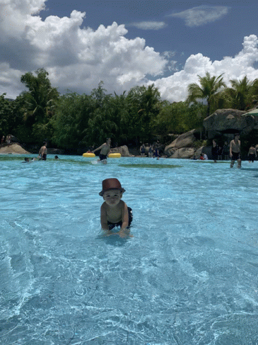 a baby wearing a hat is crawling in the water