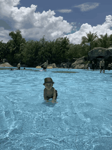 a baby wearing a hat is crawling in the water