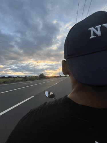 a man wearing a hat with the letter n on it is driving down a highway