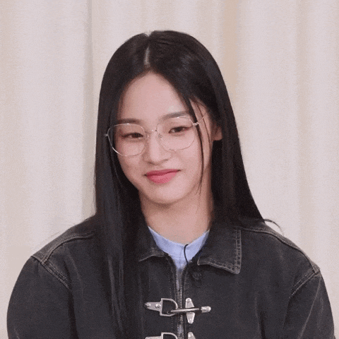 a woman wearing glasses and a black jacket is smiling .