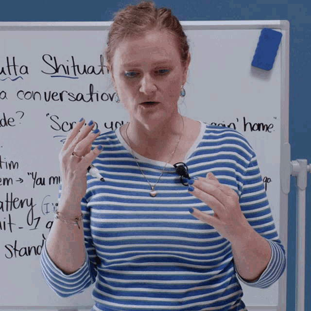 a woman in a blue and white striped shirt stands in front of a white board that says ' atta shitua ' on it