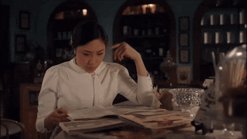 a woman in a white shirt is reading a magazine