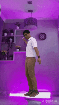a man in a white shirt and brown pants is standing in front of a purple wall ..