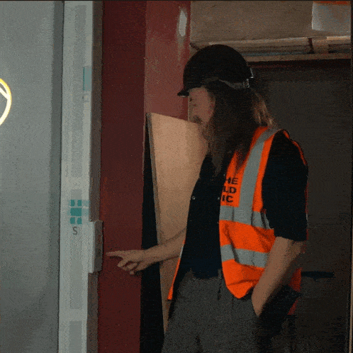 a man wearing a hard hat and an orange vest with the word ic on it