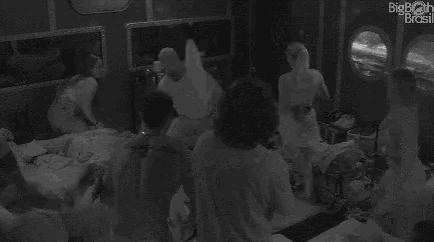 a group of people are having a pillow fight in a room .