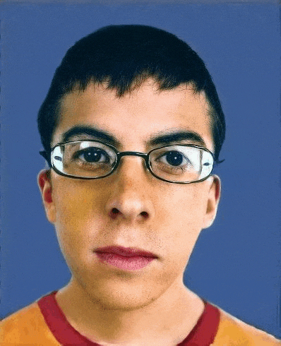 a young man wearing glasses is looking at the camera with a serious look on his face .