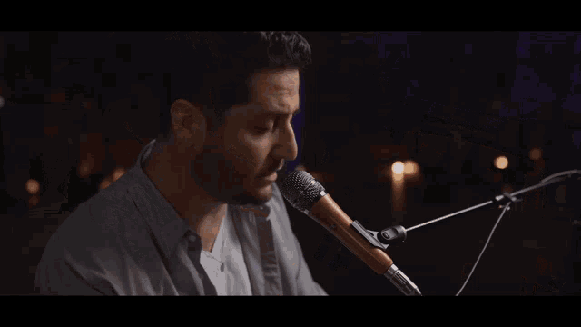 a man is playing a piano and singing into a microphone