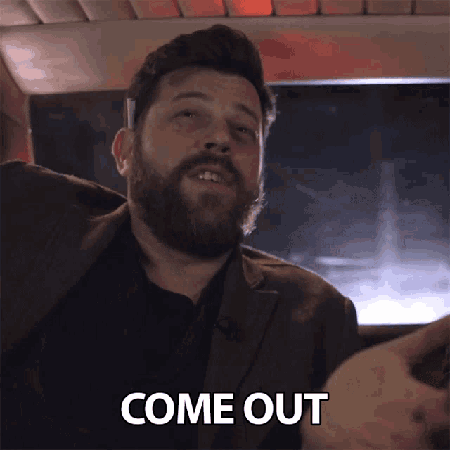 a man with a beard says come out in a car