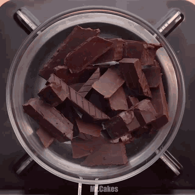 a glass bowl filled with pieces of chocolate and the words mccakes on the side