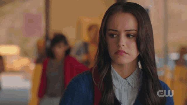 a woman in a blue sweater with the cw logo on the bottom