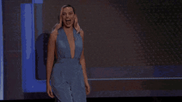 a woman in a blue dress is sitting in front of a microphone and talking into it .
