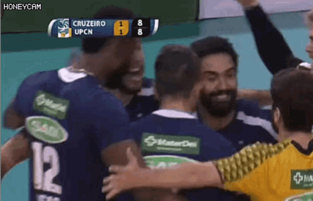 a group of volleyball players are hugging each other on the court .