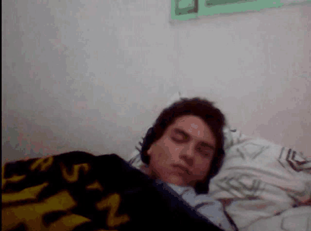 a man is sleeping in a bed with a blanket that has the letter s on it