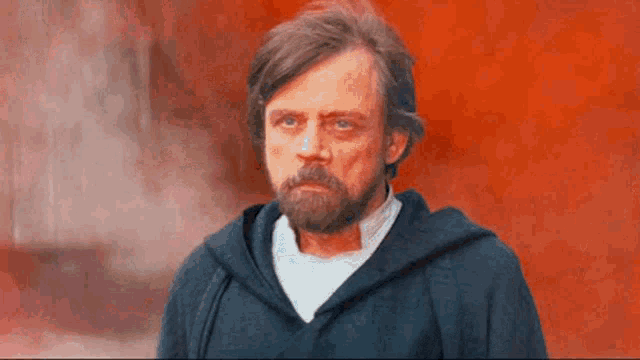 a man with a beard is wearing a hooded jacket and a white shirt .