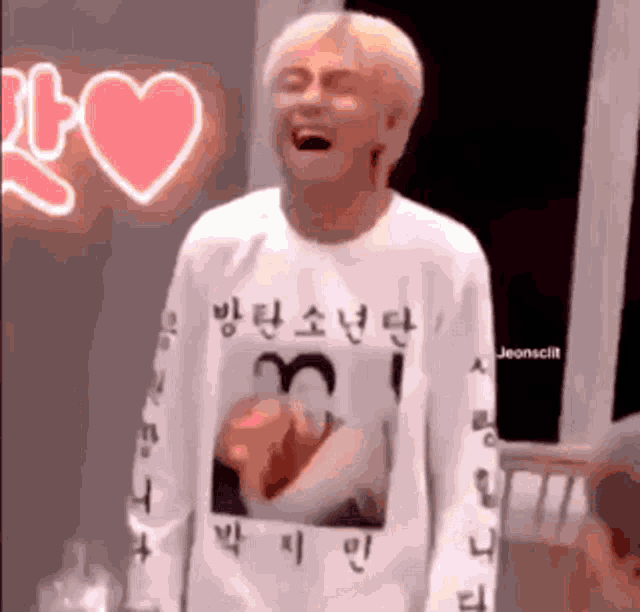 a man wearing a white t-shirt with a picture of a man on it is laughing .