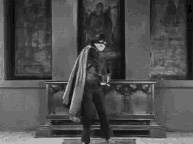 a black and white photo of a man in a costume standing in front of a painting .