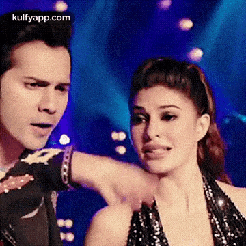 a man and a woman are dancing together on a stage and the woman is holding the man 's arm .