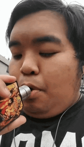 a man wearing a black shirt with the word gm on it is smoking a cigarette