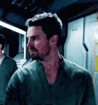 a man with a beard and a green shirt is standing in a room looking at something .