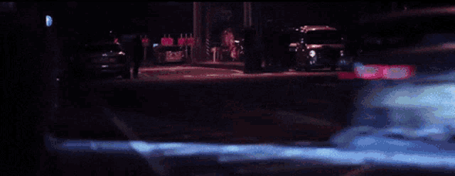 a car is driving down a dark street with a sign that says ' no parking ' on it