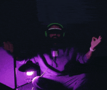 a man in a purple hoodie is wearing headphones and glasses